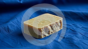 A rectangular textured bar of soap rests on crumpled blue fabric