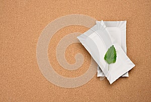 Rectangular white paper plates and a green leaf on a brown cork background. No plastic concept, top view