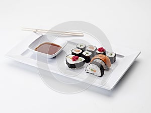 Rectangular white tray filled with makis and sweet and sour sauce photo