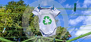 Recycle clothes icon on Babygro drying outside on washing line with 100% Recycled text