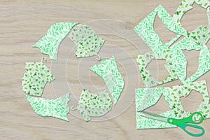 Recycle clothes icon symbol recycle sign cut from reuse textiles on a wooden background with scissors and cut out fabric