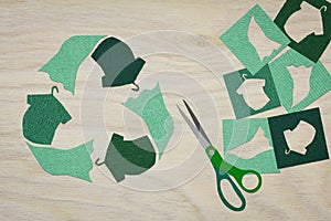 Recycle clothes symbol recycle sign cut from reuse textiles on a wooden background with scissors and cut out fabric, sustainable