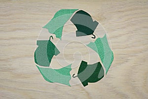 Recycle clothes symbol recycle sign cut from reuse textiles on a wooden background, sustainable fashion concept