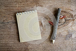 Recycle notebook with wooden pencil on old wooden table