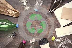 Recycle symbol and plastic, paper, glass on wood table