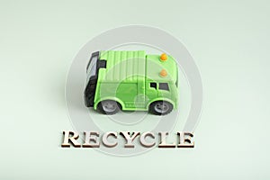 Recycle text. Toy garbage truck and recycle text on a green background