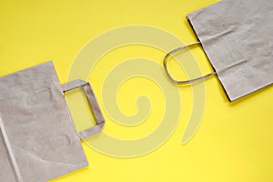 Recycled brown paper shopping bag with handle, isolated on yellow background, flat lay, mockup. Two folded empty paper bag.