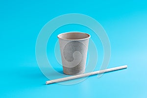 Recycled paper cup and drinking straw on blue background. Eco-friendly biodegradable drinkware. Zero waste concept