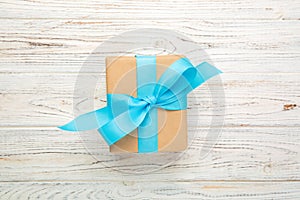 Recycled paper gift box with Blue ribbon on old wooden white background.Top view