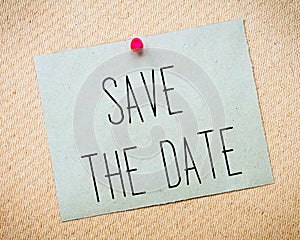 Recycled paper note pinned on cork board.Save the Date Message