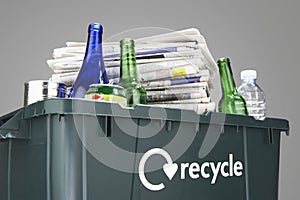 Recycling bin filled with waste paper and bottles close-up