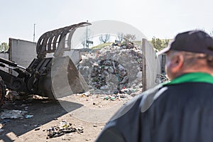 Recycling center worker looking at an unsorted garbage heap