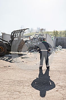 Recycling center worker looking at an unsorted garbage heap