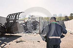 Recycling center worker looking at an unsorted garbage heap