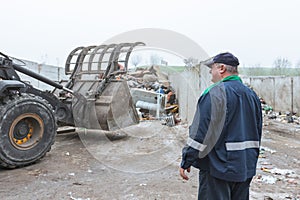 Recycling center worker looking at an unsorted garbage heap, rear view