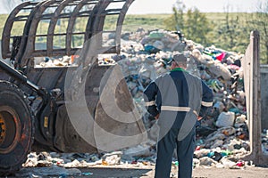 Recycling center worker looking at an unsorted garbage heap, rear view