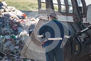 Recycling center worker looking at an unsorted garbage heap, rear view