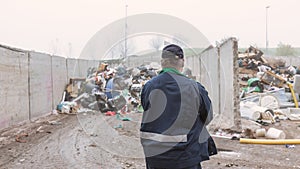 Recycling center worker looking at an unsorted garbage heap, rear view