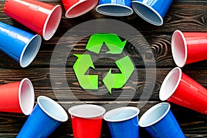 Recycling and eco concept with plastic cups frame on wooden background top view