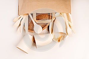 Recycling,eco-friendly concept.Disposable eco cutlery,plates,spoons,knives,forks on a light background.Craft paper bag