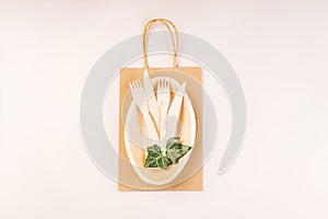 Recycling,eco-friendly concept.Disposable eco cutlery,plates,spoons,knives,forks on a light background.Craft paper bag