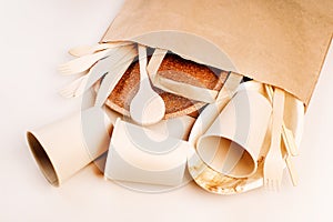 Recycling,eco-friendly concept.Disposable eco cutlery,plates,spoons,knives,forks on a light background.Craft paper bag