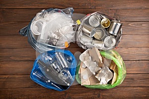 Recycling and ecology concept. Sorting household waste - plastic, paper, metal, captured from above, flat lay. Wooden background