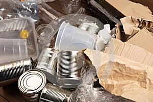 Recycling and ecology concept. Sorting household waste - plastic, paper, metal, captured from above, flat lay. Wooden background