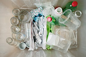 Recycling and ecology. Sorting segregating household waste paper, glass, plastic into contaner captured from above, flat lay.