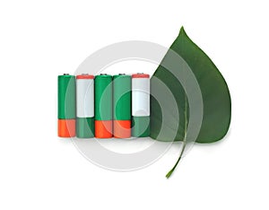 Recycling, energy, environment and ecology concept - close up of green alkaline batteries with leaf over white background