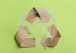 Recycling symbol cut out of kraft paper on green background