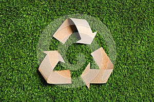 Recycling symbol cut out of kraft paper on green grass