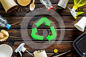 Recycling symbol and different garbage, paper cup, flatware, plastic bottle, can for ecology wooden background top view