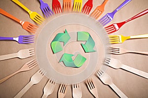 Recycling symbol, plastic and wooden forks on background, flat lay