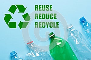 Recycling symbol with reuse reduce recycle text and plastic bottles on blue background