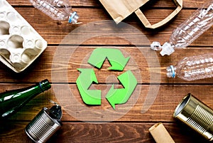 Recycling symbol with waste on wooden background top view