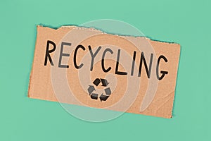 Recycling text and arrow symbol on piece of cardboard