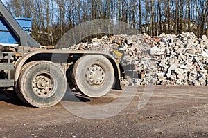 A recycling truck with rubble in the background