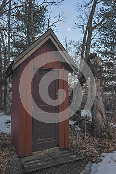 Red abandoned outhouse in the woods under the moon and moonlight at dusk with a fallen tree - taken near the Governor Knowles Stat photo