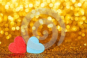 Red abd blue little decorative hearts against gold yellow sparkle glitter background with amazing bokeh lights. Love or romantic