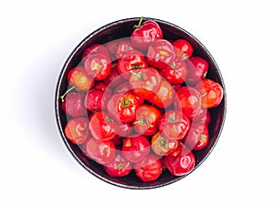 Red acerola cherries fruit in a ceramic bowl isolated on a white background.