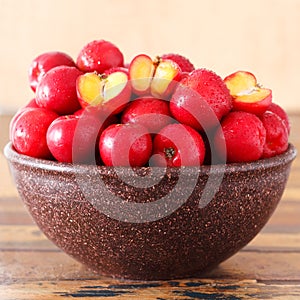 Red acerola (malpighia glabra), tropical fruit in brown bowl