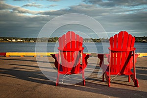 Red adirondack chairs in front of water