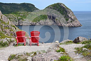 Red Adirondack chairs overlooking the ocean and coastline