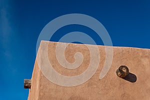 Red adobe exterior corner, exposed vigas, bright blue sky creative copy space