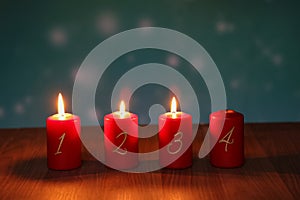 Red Advent candles stand on a wooden floor