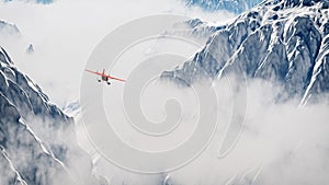 Red airplane flying over snow mountains in the clouds.