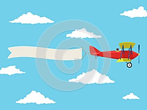 Red airplane with pilot and advertising banner in the cloudy sky