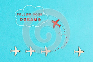 Red airplanes takes a different direction, flying to the cloud with the phrase follow your dreams, motivation and coaching concept