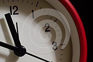 Red alarm clock close up. It's showing ten minutes to twelve o'c photo